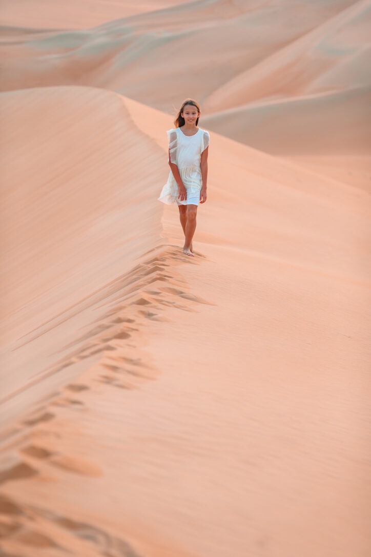 Girl among dunes in desert in United Arab Emirates