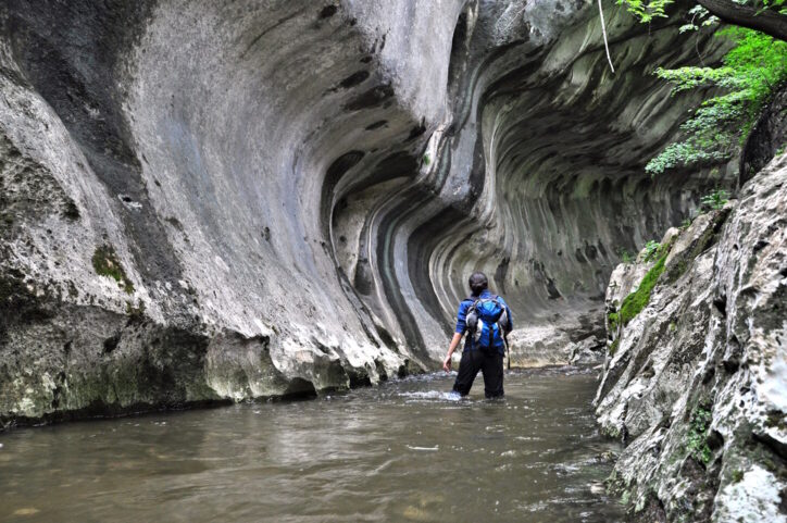 Hiker Passing Through the Water in a Gorge